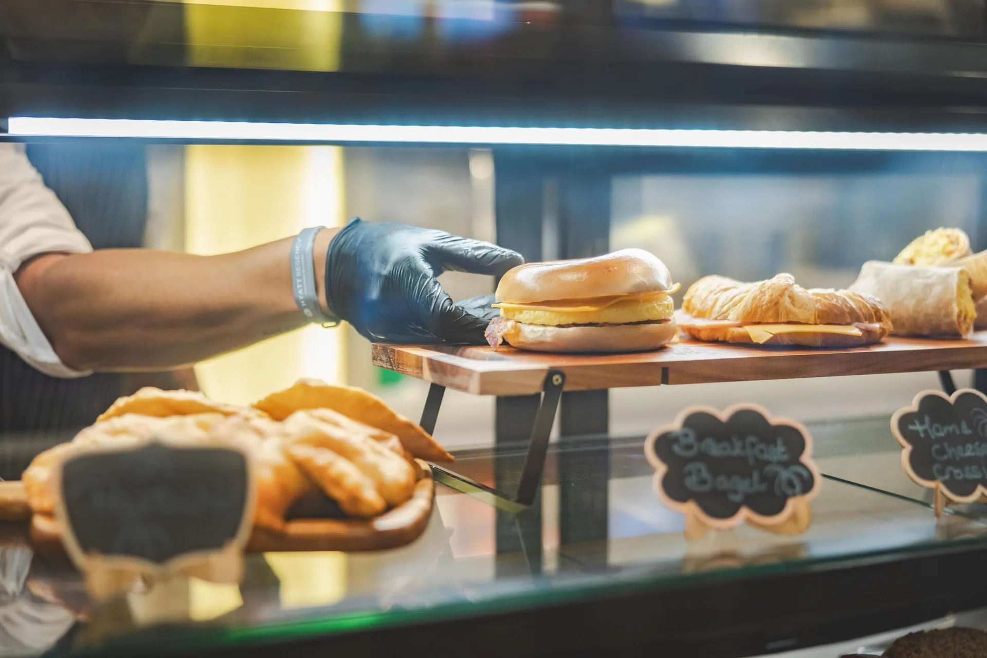 A server places a bagel sandwich beside pastries in a display case at Hyatt Regency Aruba Resort and Casino.