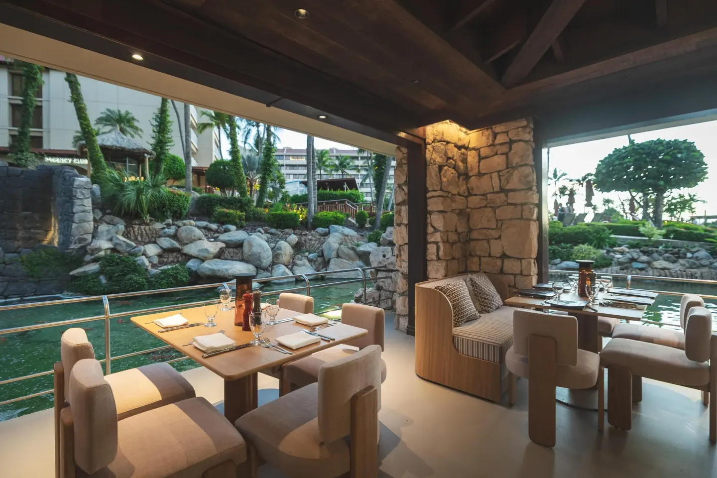 Waterfront dining tables beside a lagoon and stone landscaping at Hyatt Regency Aruba Resort and Casino.