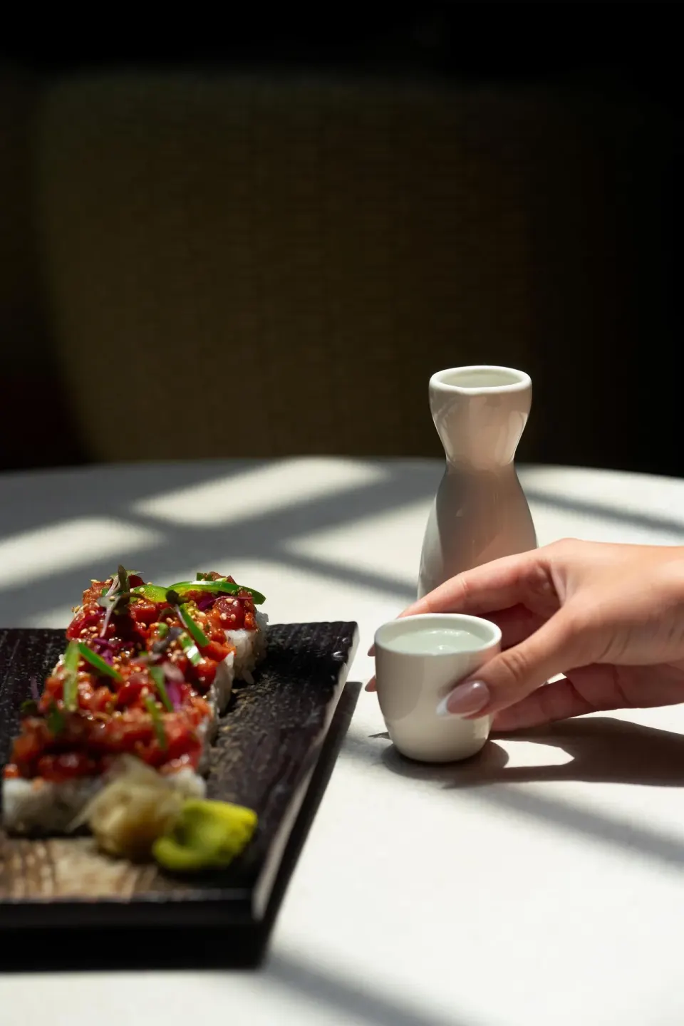 Sushi roll and a hand holding a small cup on a table at Hyatt Regency Aruba Resort and Casino.