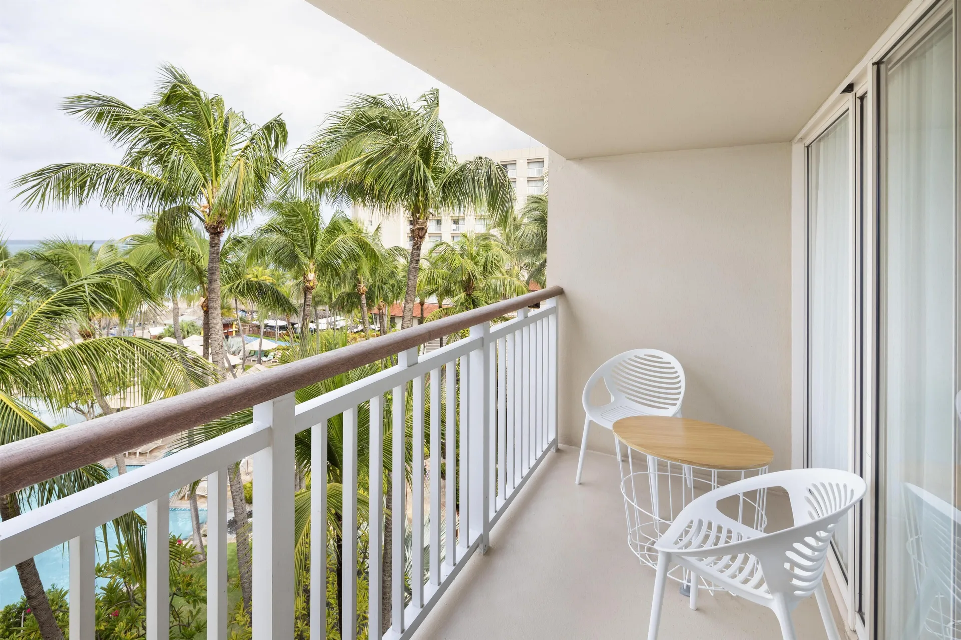 Cayena Suite Resort View balcony with chairs and palm view at Hyatt Regency Aruba Resort and Casino.