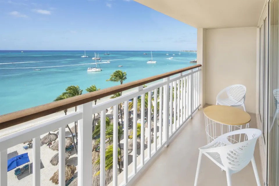 Balcony with white chairs overlooking the ocean at Hyatt Regency Aruba Resort and Casino.