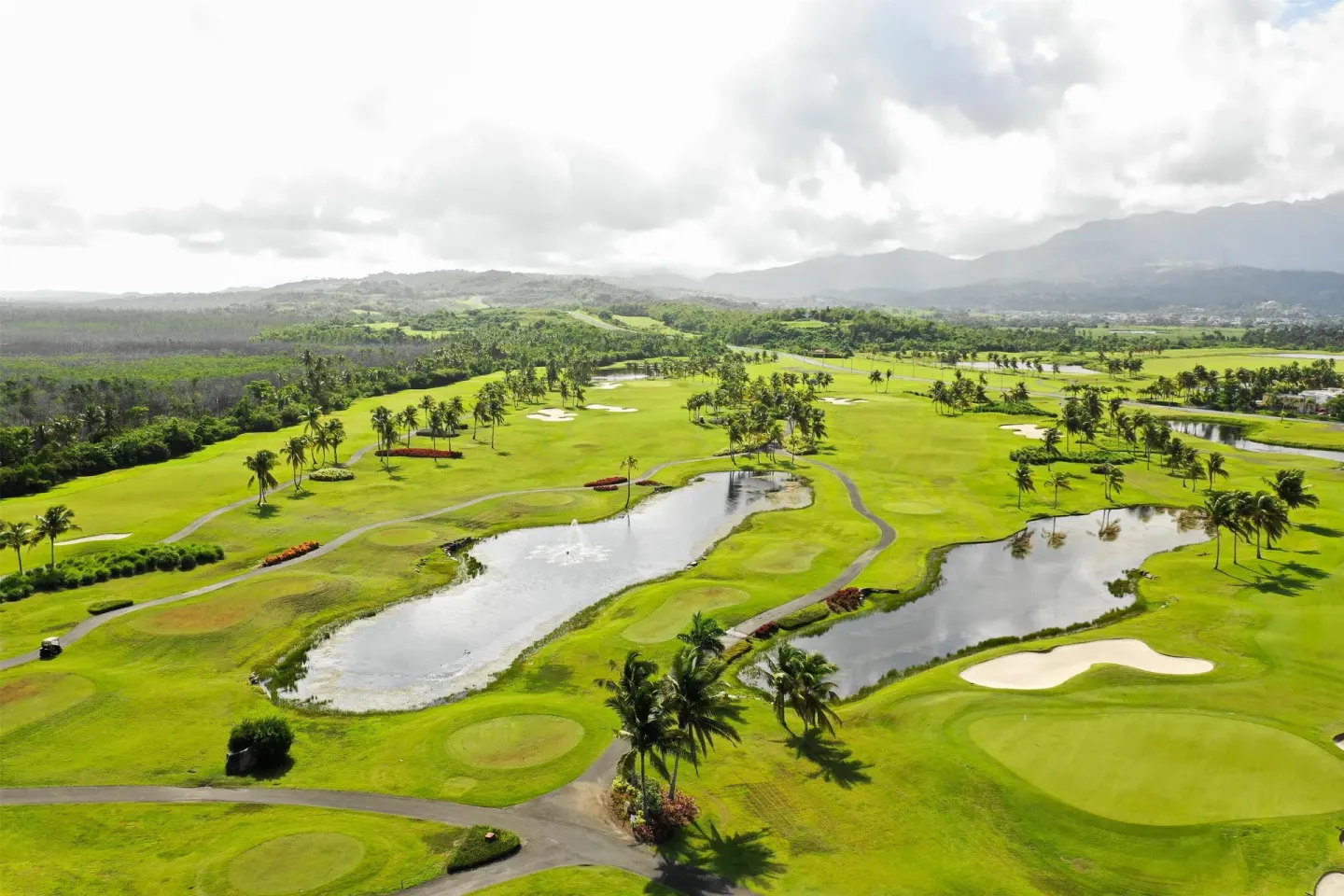 Wide aerial view of golf fairways, ponds, and mountains at Hyatt Regency Grand Reserve Puerto Rico.