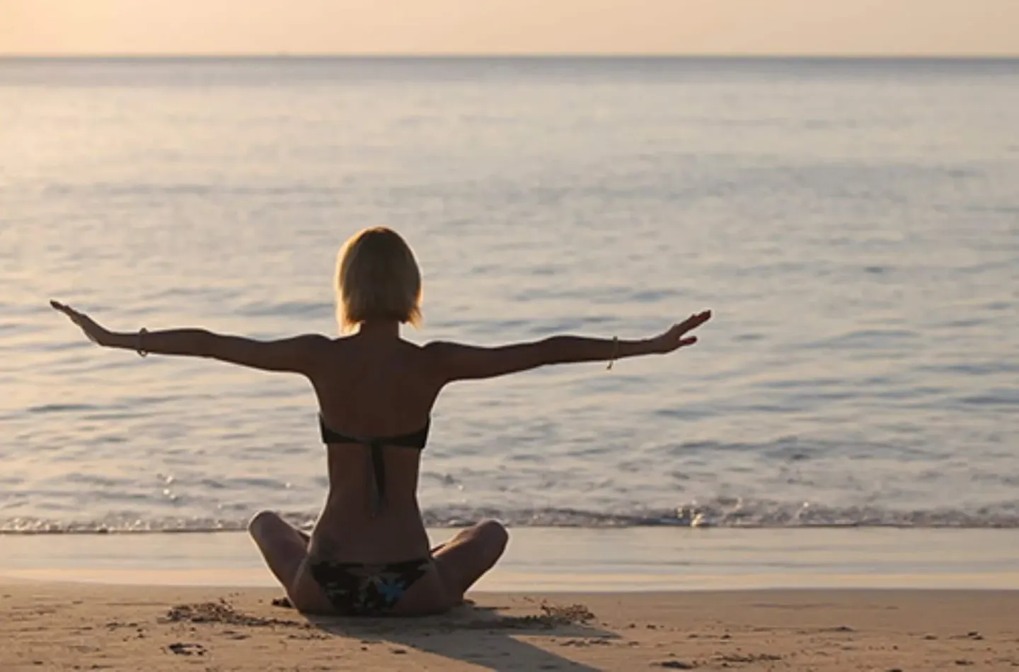 A guest meditates on the beach at sunset at Hyatt Regency Grand Reserve Puerto Rico.