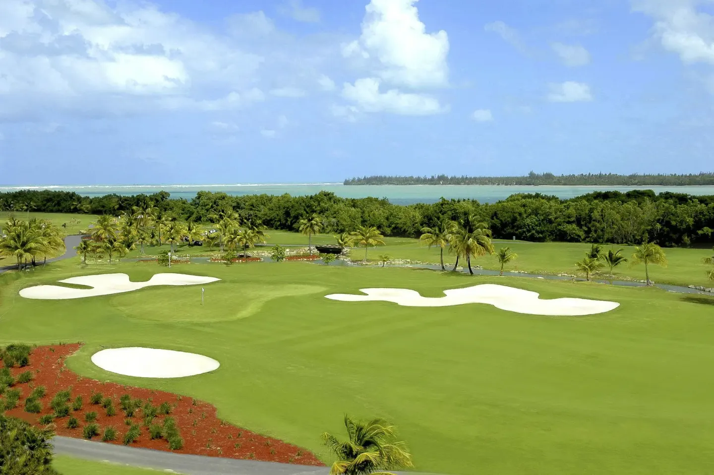 Golf green with white sand bunkers and ocean beyond at Hyatt Regency Grand Reserve Puerto Rico.