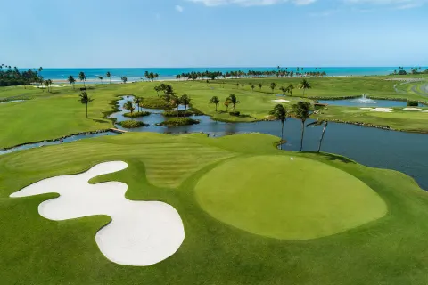 Golf green beside water, palms, and ocean horizon at Hyatt Regency Grand Reserve Puerto Rico.