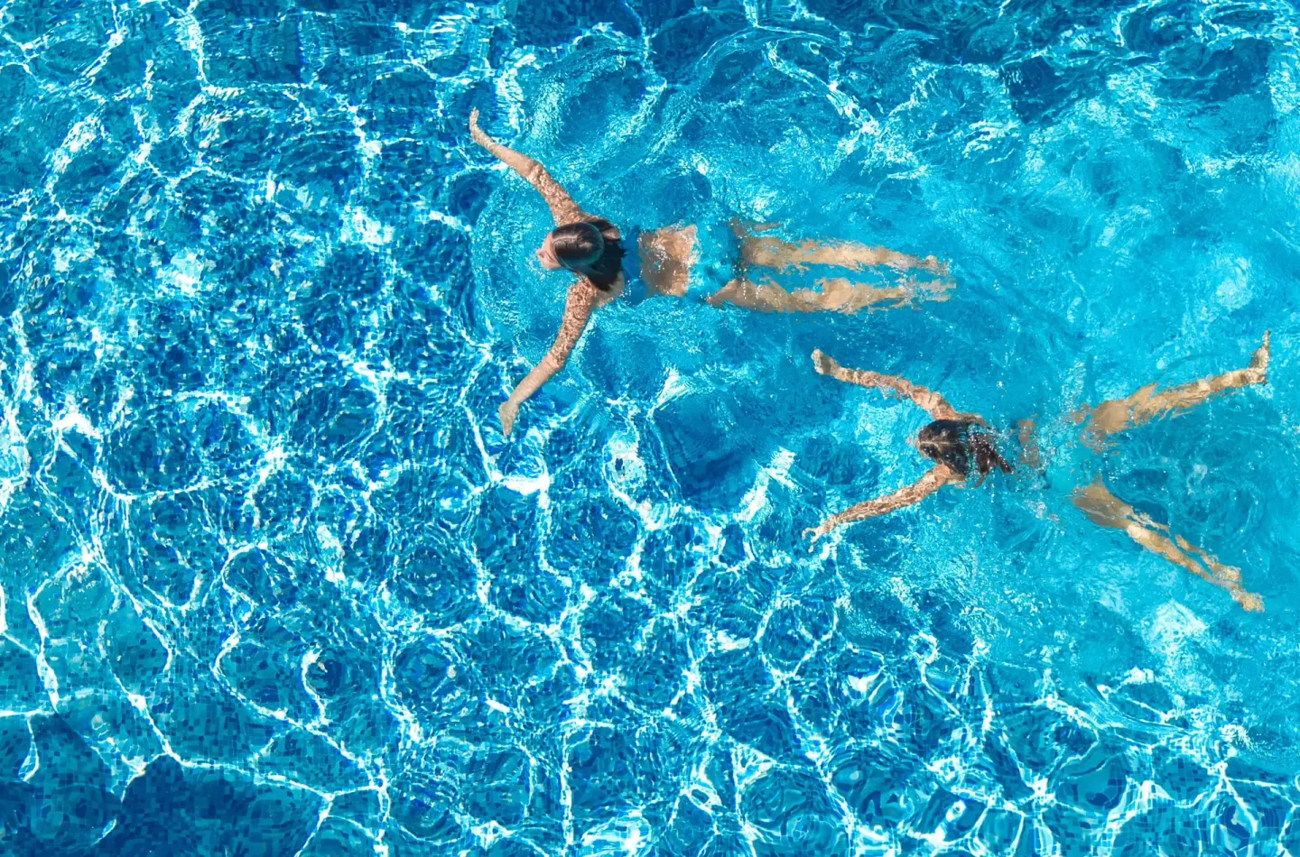 Two swimmers in a bright blue pool at Hyatt Regency Grand Reserve Puerto Rico.