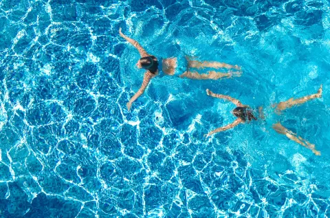 Two swimmers in a bright blue pool at Hyatt Regency Grand Reserve Puerto Rico.