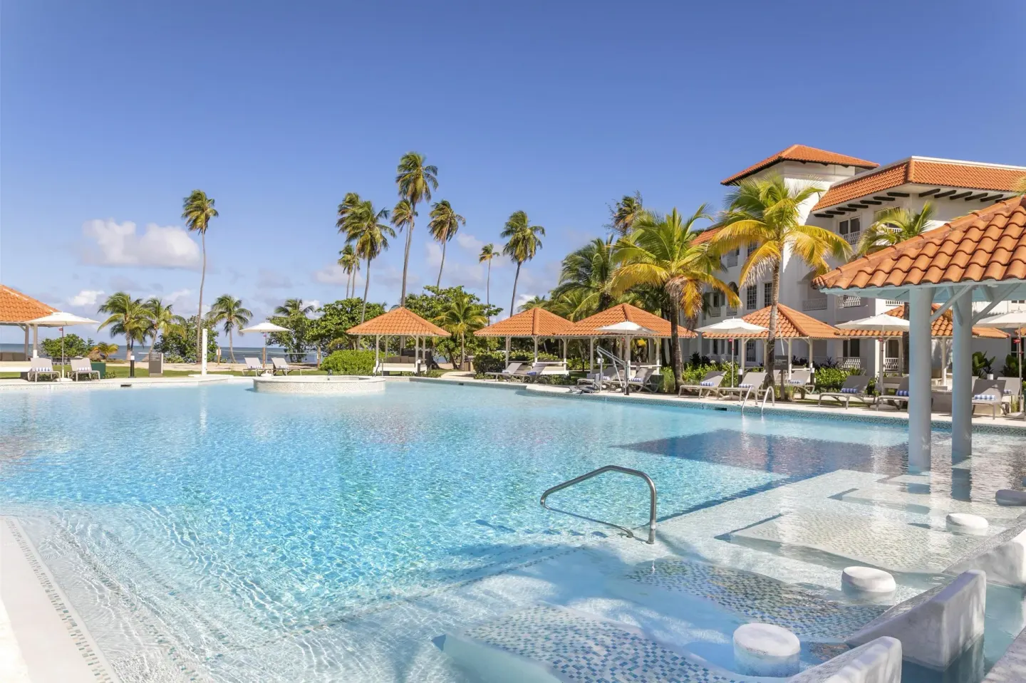 Resort pool with shallow loungers and tiled-roof pavilions at Hyatt Regency Grand Reserve Puerto Rico.