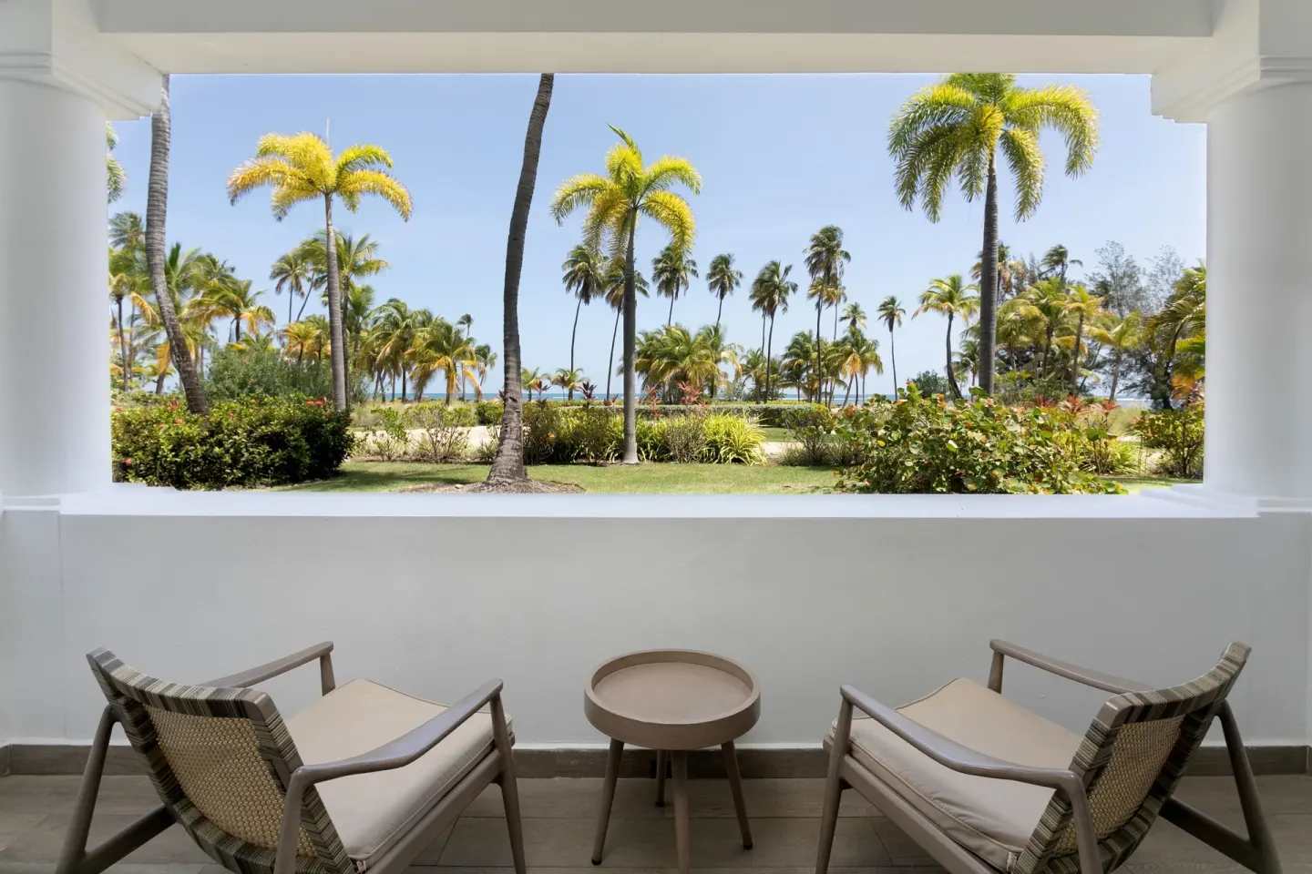 Deluxe Ocean View room terrace at Hyatt Regency Grand Reserve Puerto Rico with chairs and palm-framed sea view.