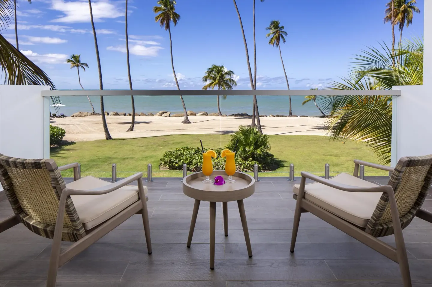 Oceanfront balcony with chairs, drinks and palm-lined beach at Hyatt Regency Grand Reserve Puerto Rico.