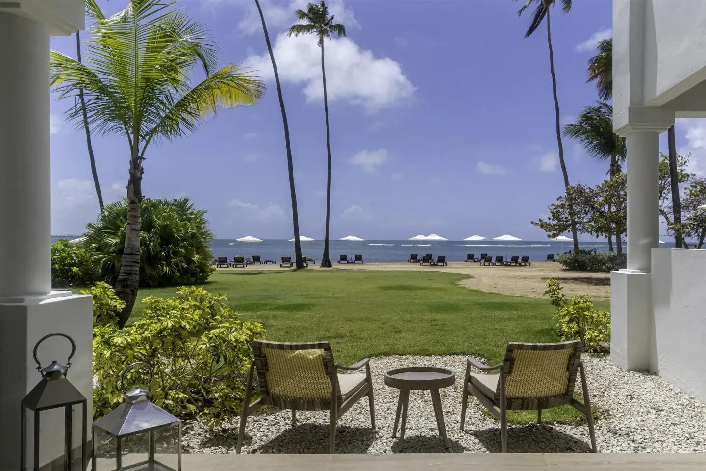 Oceanfront terrace seating facing lawn, palms and sea at Hyatt Regency Grand Reserve Puerto Rico.
