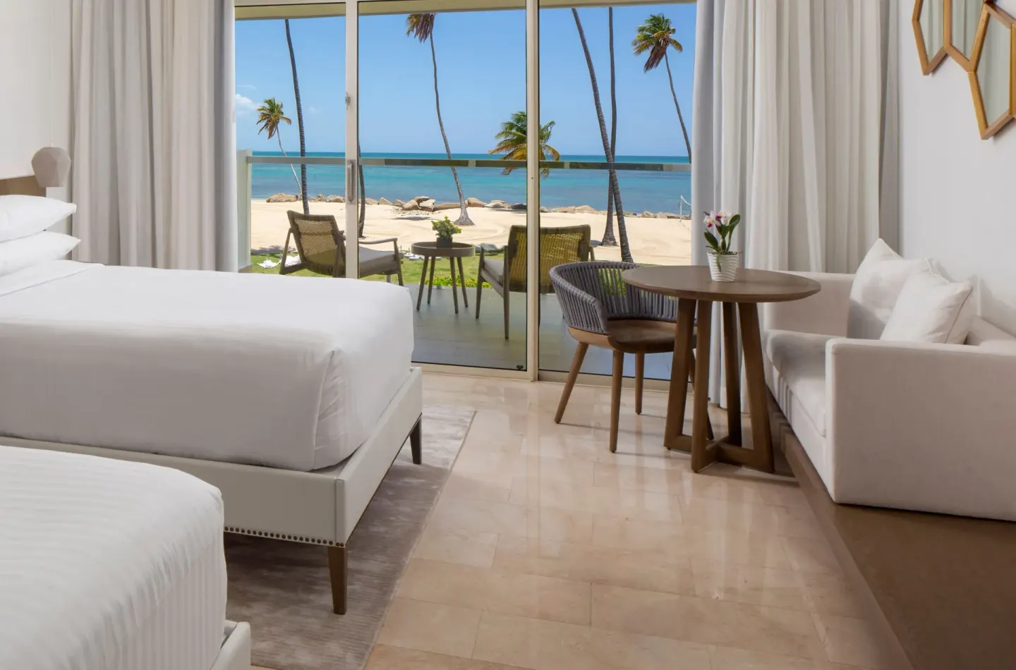 Deluxe Oceanfront room with beds, seating, terrace, palms and ocean at Hyatt Regency Grand Reserve Puerto Rico.