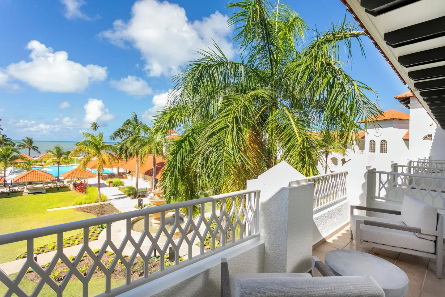 Deluxe Villa ocean-view balcony overlooking palms and pool at Hyatt Regency Grand Reserve Puerto Rico.