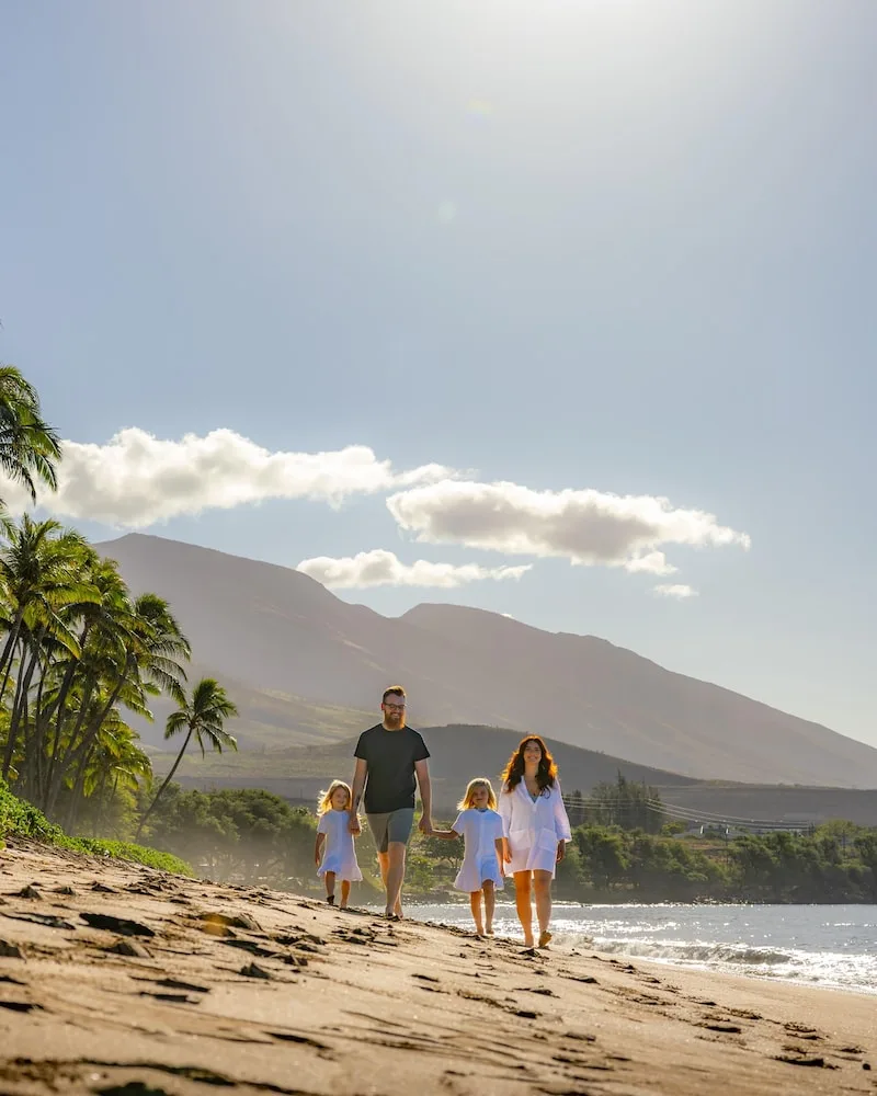 Family walking along the beach with mountain backdrop at Hyatt Regency Maui Resort & Spa.