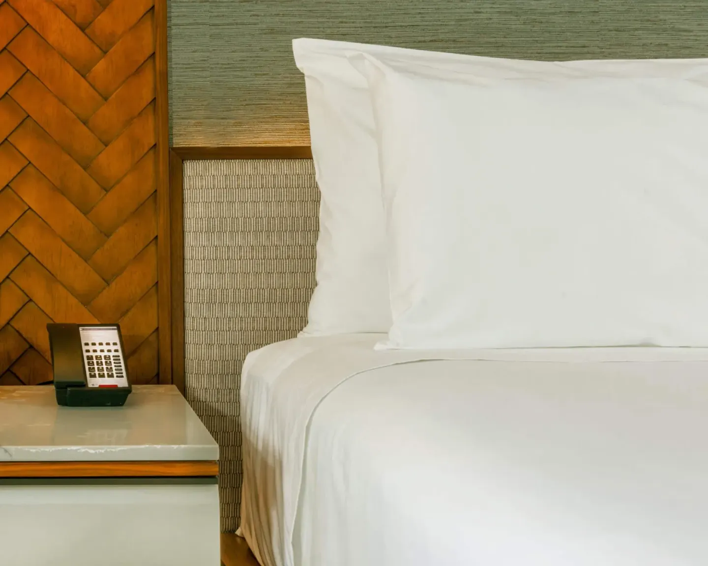 Close-up of a guest room bed and bedside phone at Hyatt Regency Maui Resort & Spa.