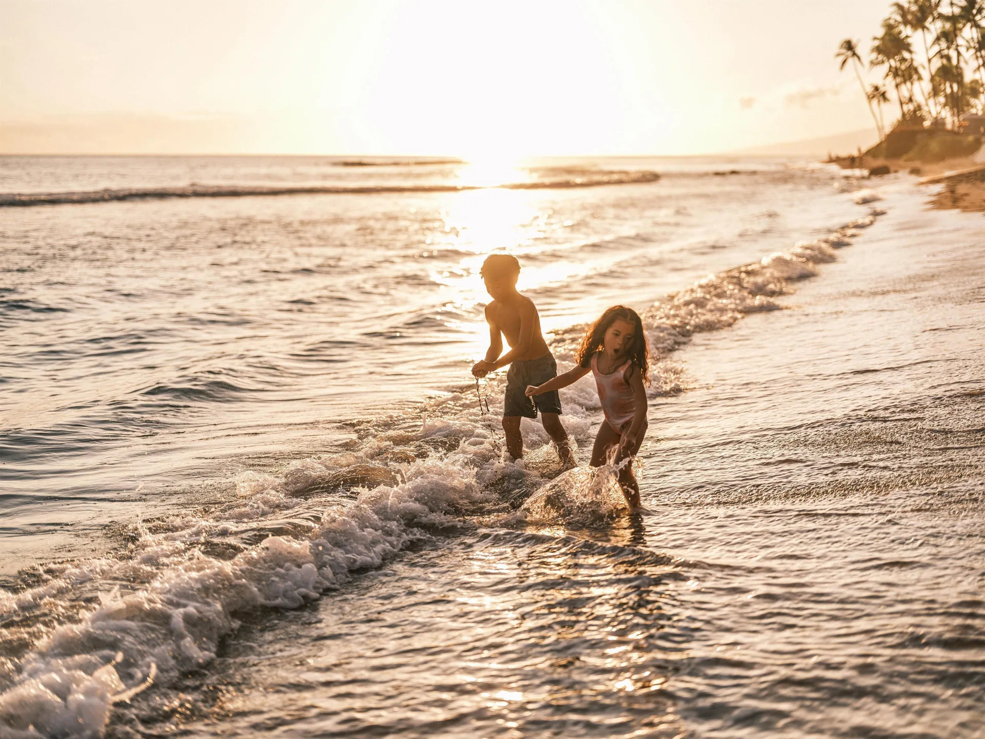 Children playing in sunset surf near Hyatt Regency Maui Resort & Spa.