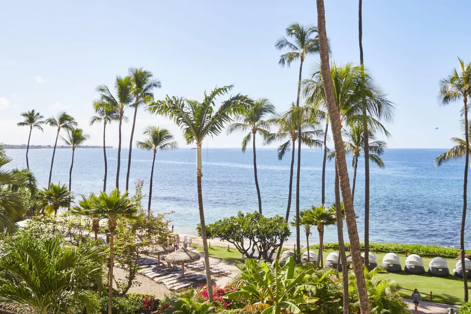 Ocean view with palms, beach seating and coastline at Hyatt Regency Maui Resort & Spa.