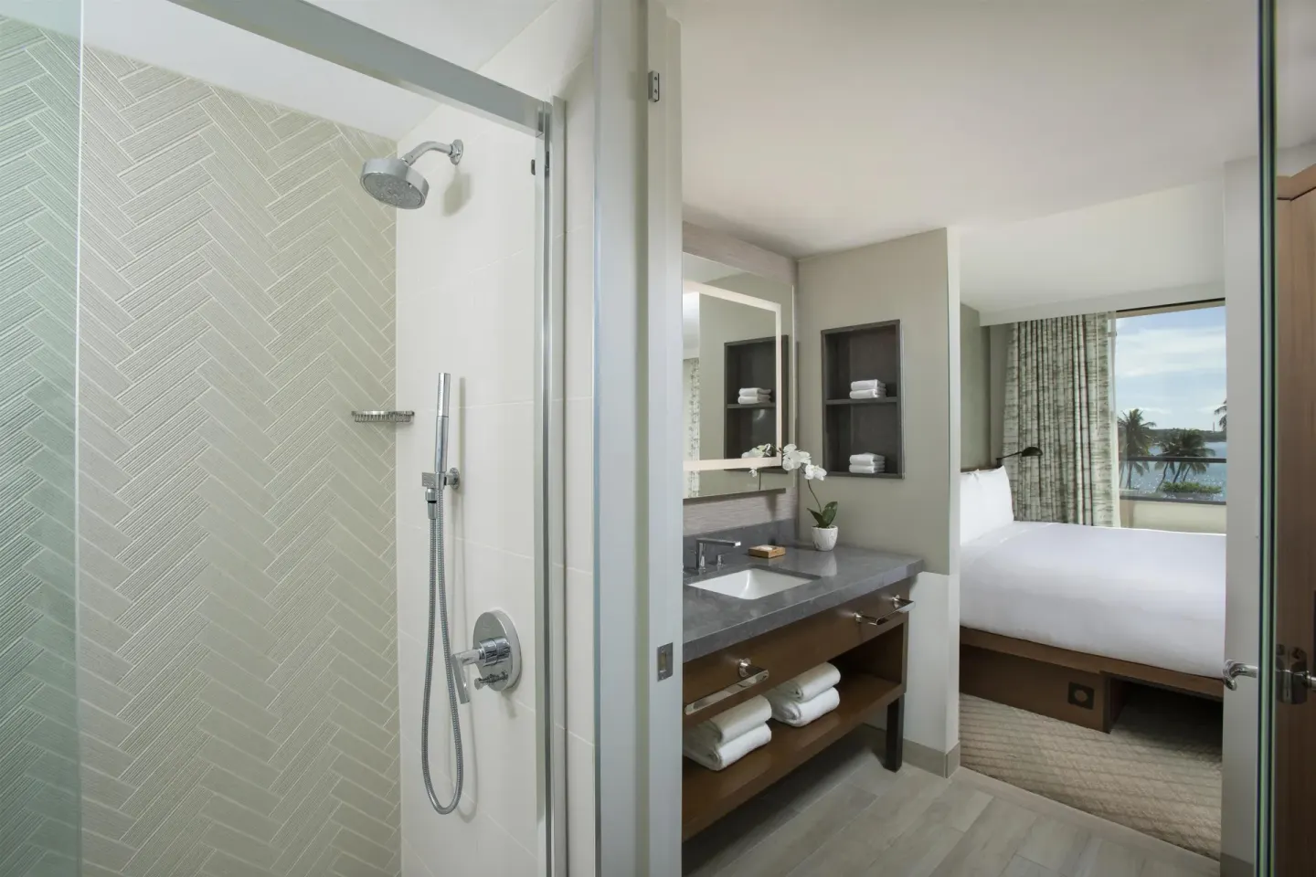 Bathroom vanity, walk-in shower, king bed, and ocean view in a corner room at Hyatt Regency Maui Resort & Spa.