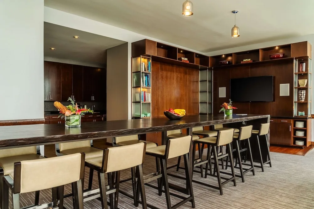 Lounge seating with a long high table and wall-mounted TV at Hyatt Regency Trinidad.