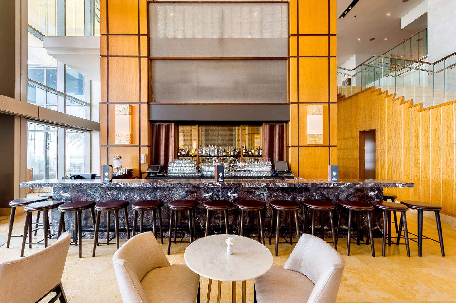 Lobby bar with stools, lounge chairs, and tall wood panels at Hyatt Regency Trinidad.