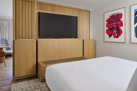 Guest room king bed facing a wood media wall at Hyatt Regency Waikiki Beach Resort & Spa.