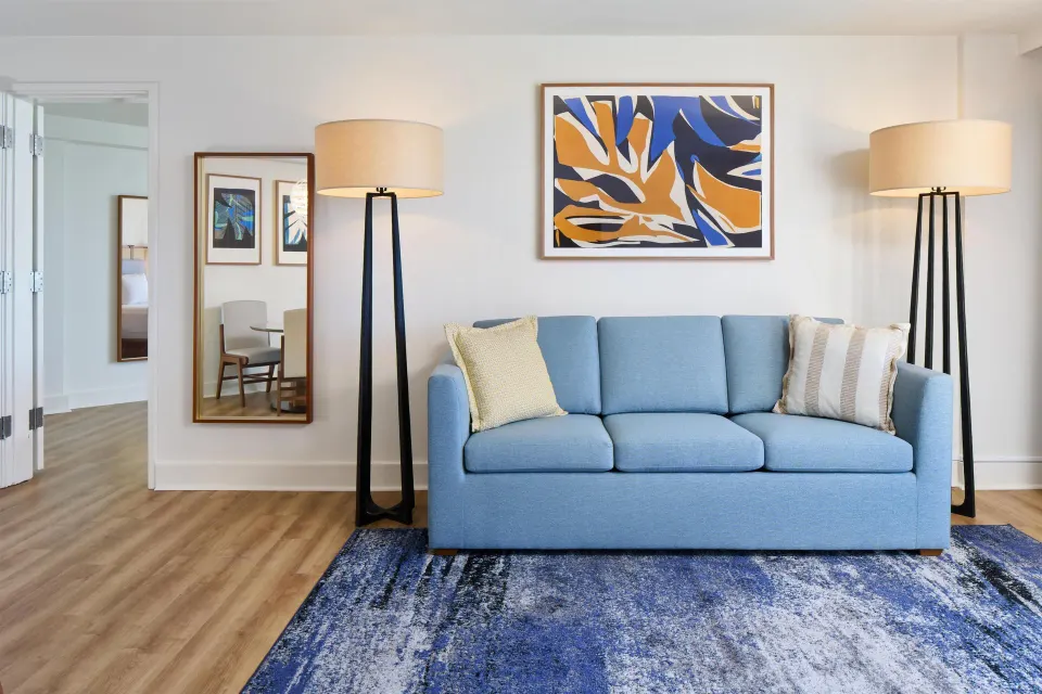 Blue sofa and floor lamps in an ocean front suite living room at Hyatt Regency Waikiki Beach Resort & Spa.