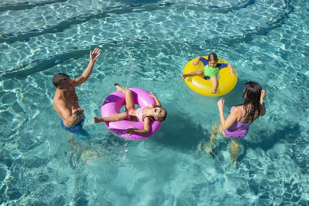 Family playing with inflatable rings in the pool at Hyatt Vacation Club at Ka'anapali Beach.
