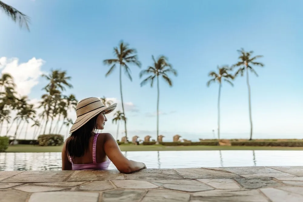 Guest relaxing in the pool with palm trees beyond at Hyatt Vacation Club at Ka'anapali Beach.