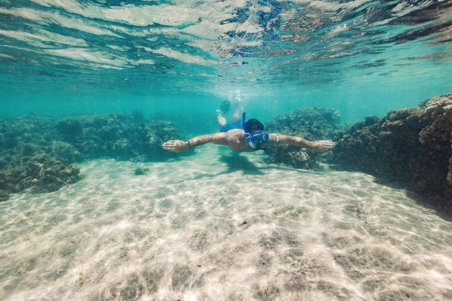 Snorkeler swimming over coral and sand near Hyatt Vacation Club at Ka'anapali Beach.