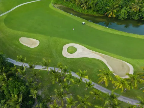 Overhead view of golf bunkers, palms, and a waterway at Iberostar Selection Bávaro Suites.