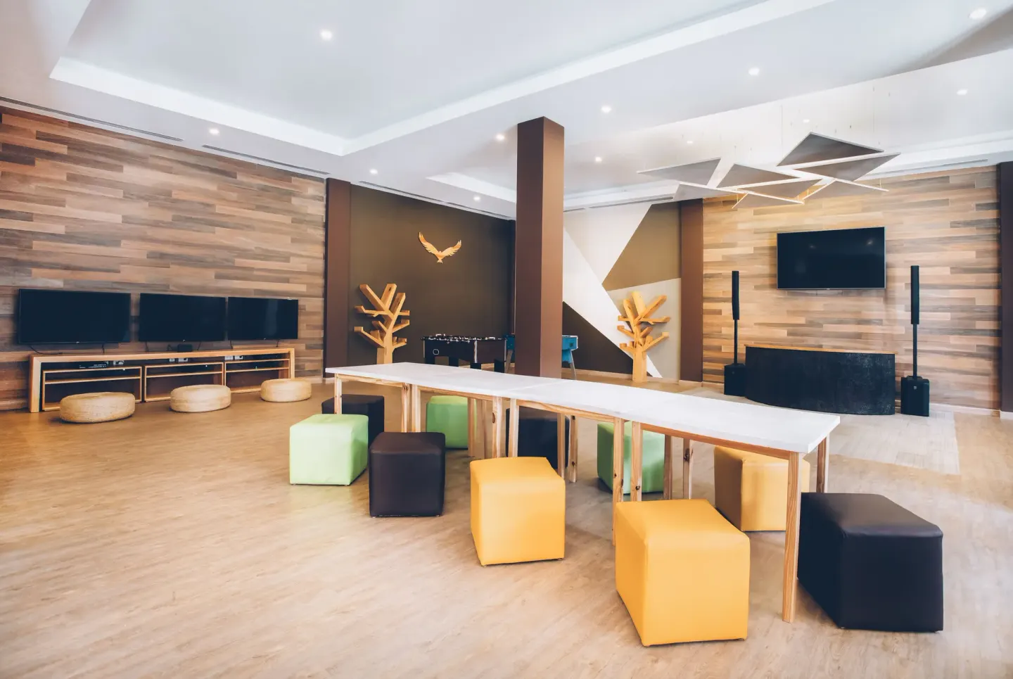 Modern lounge with screens, tables, and cube seats at Iberostar Selection Bávaro Suites.