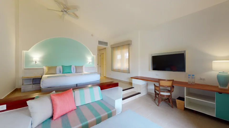 Junior Suite with king bed, sofa, desk, TV, and lamp at Iberostar Selection Bávaro Suites.