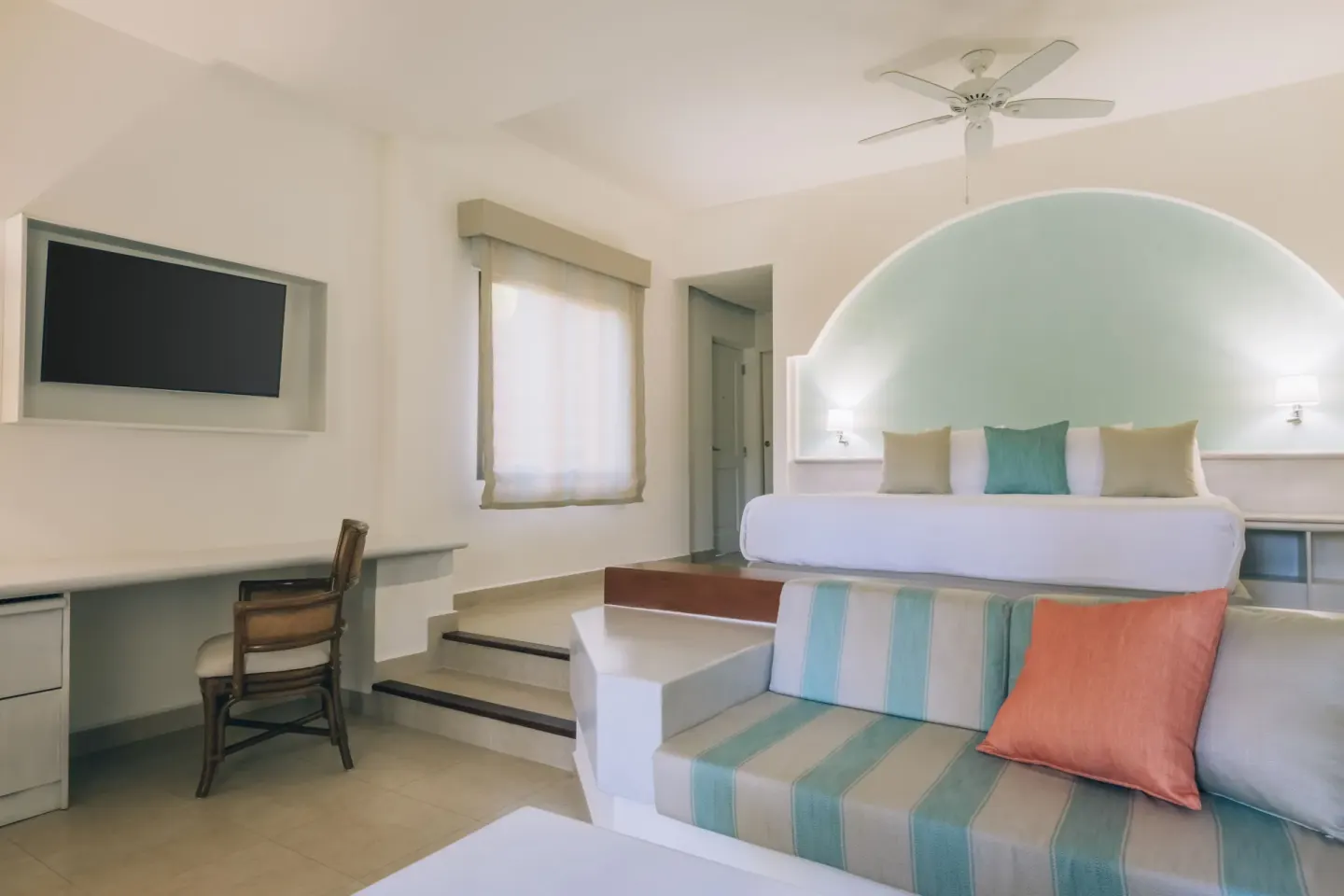 Junior Suite with king bed, sofa, desk, and wall TV at Iberostar Selection Bávaro Suites.