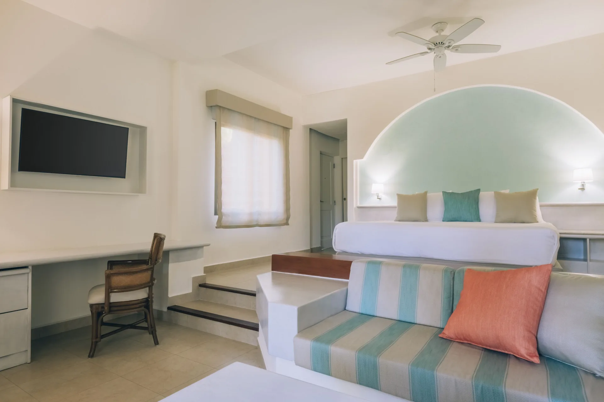 Junior Suite with king bed, sofa, desk, and wall TV at Iberostar Selection Bávaro Suites.