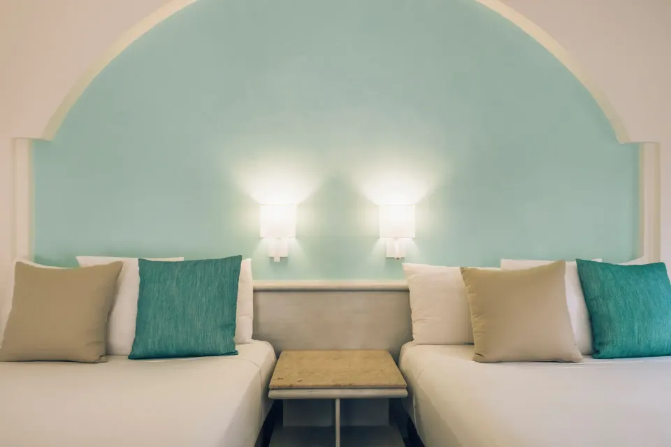 Two beds with turquoise headboard and wall lights at Iberostar Selection Bávaro Suites.