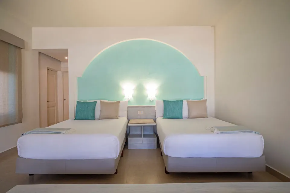 Junior Suite with two beds and arched turquoise headboard at Iberostar Selection Bávaro Suites.