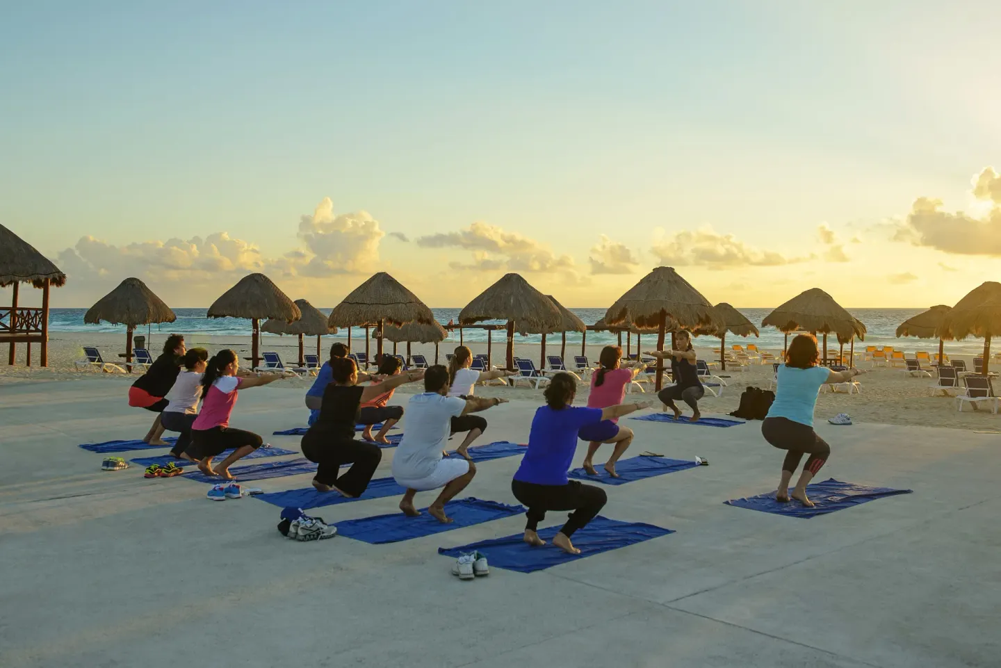 Beach fitness class on mats at sunset at Iberostar Selection Cancún.