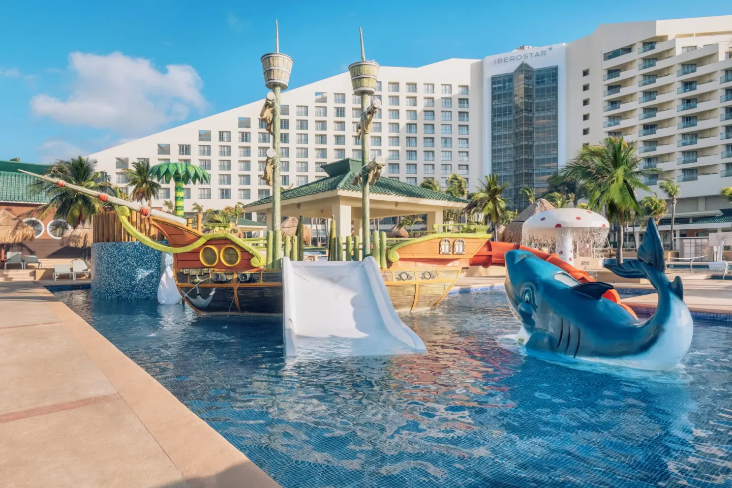 Children’s splash pool with ship slides and hotel tower at Iberostar Selection Cancún.