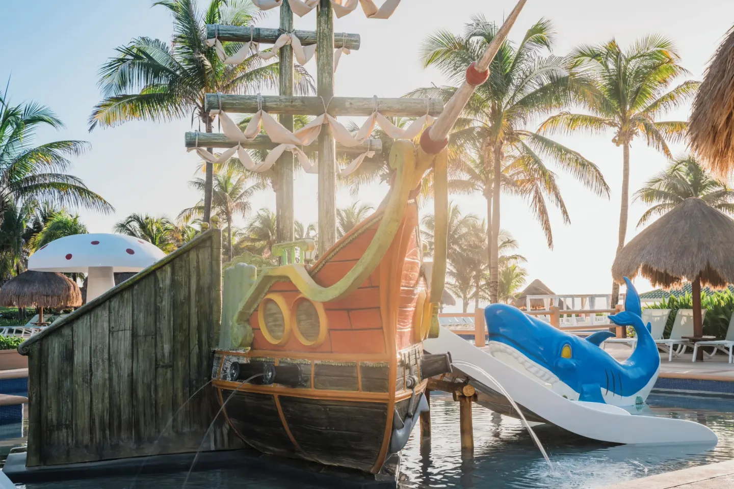 Pirate ship water play area with slides and palms at Iberostar Selection Cancún.