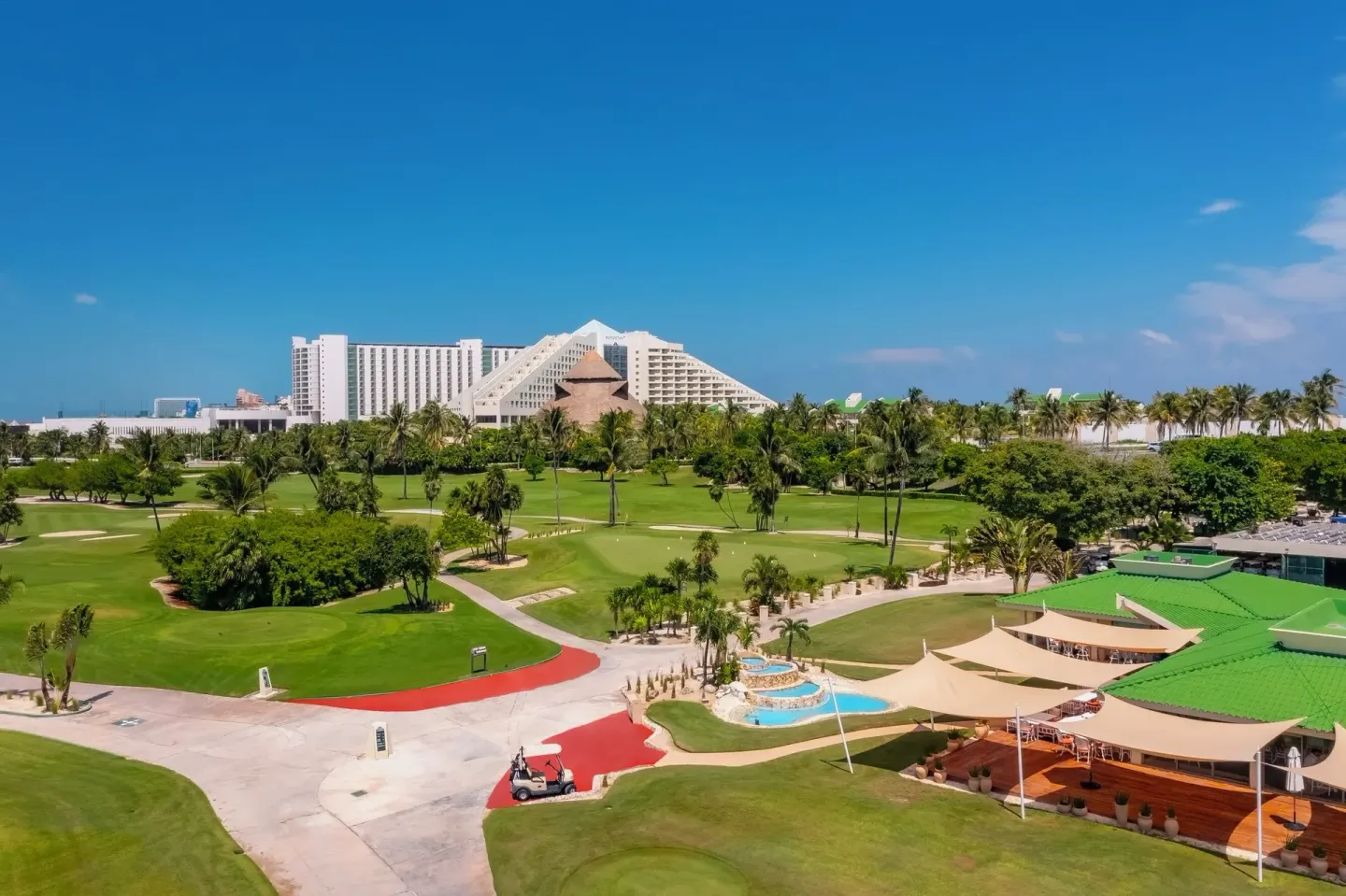 Golf course and resort buildings at Iberostar Selection Cancún under a clear blue sky.