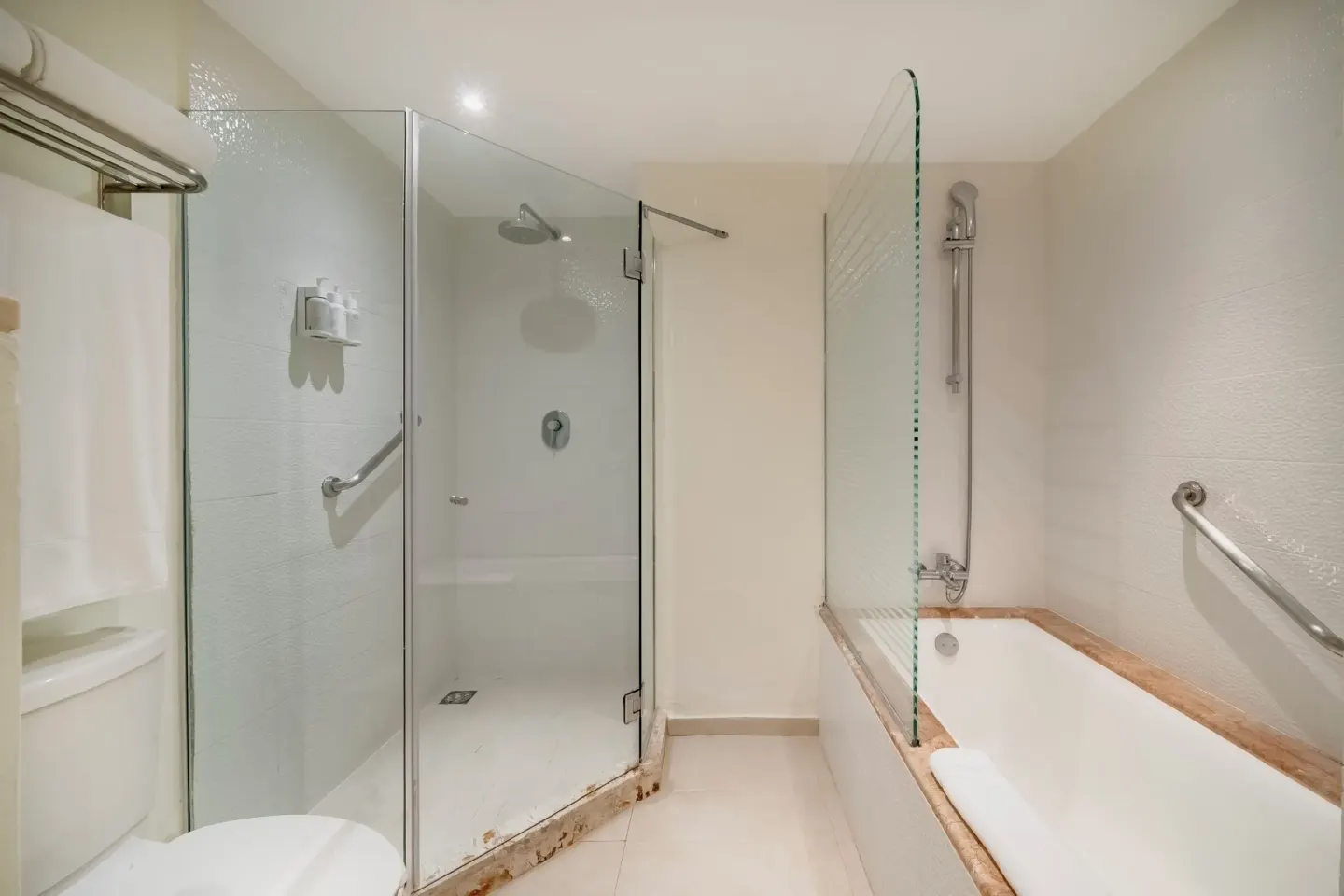 Bathroom with glass shower, bathtub, towels, and grab bars at Iberostar Selection Cancún.
