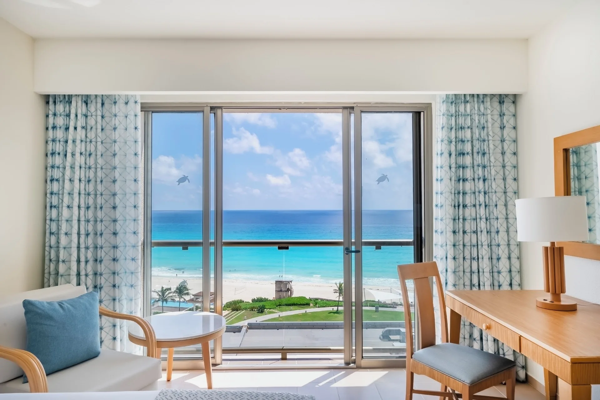 Guest room sitting area and balcony ocean view at Iberostar Selection Cancún.