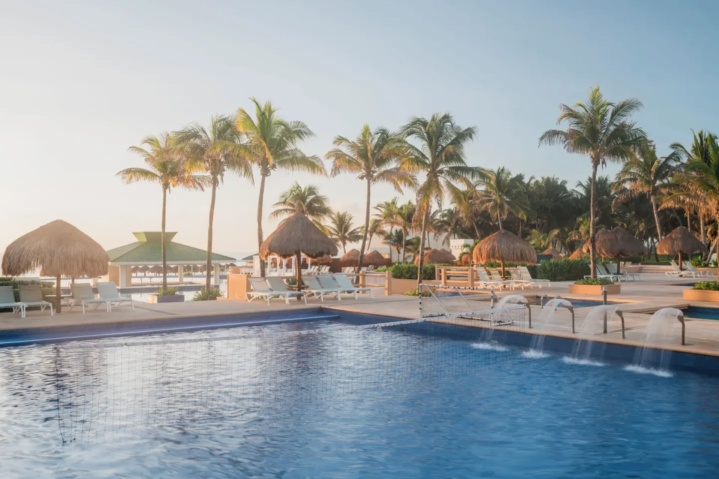 Pool with water features, palms, loungers, and palapas at Iberostar Selection Cancún.