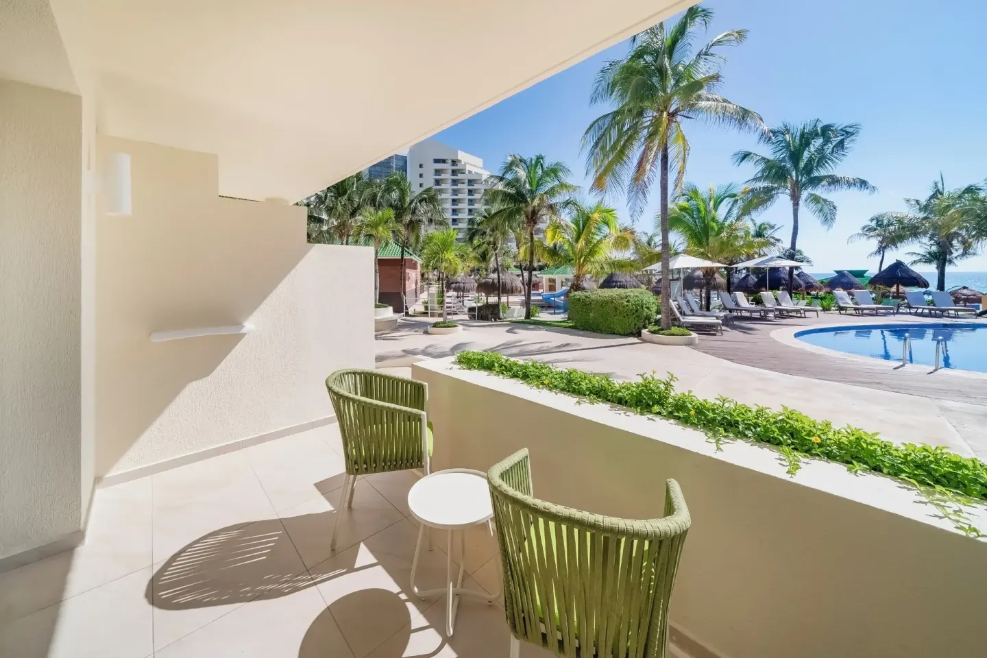 Terrace seating beside the pool deck and palms at Iberostar Selection Cancún.