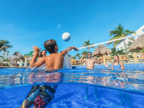 Guests playing volleyball in the resort pool at Iberostar Selection Cancún.