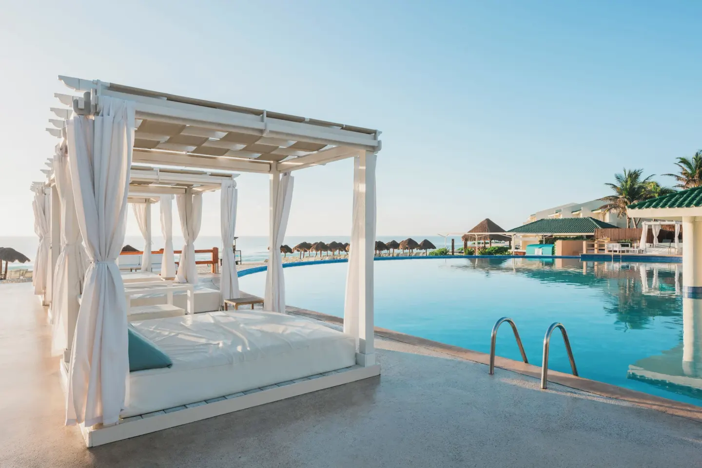 White cabanas and loungers beside the oceanfront pool at Iberostar Selection Cancún.