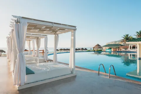 White cabanas and loungers beside the oceanfront pool at Iberostar Selection Cancún.
