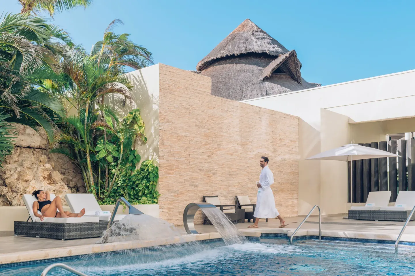 Spa pool area with loungers, waterfalls, and tropical landscaping at Iberostar Selection Cancún.