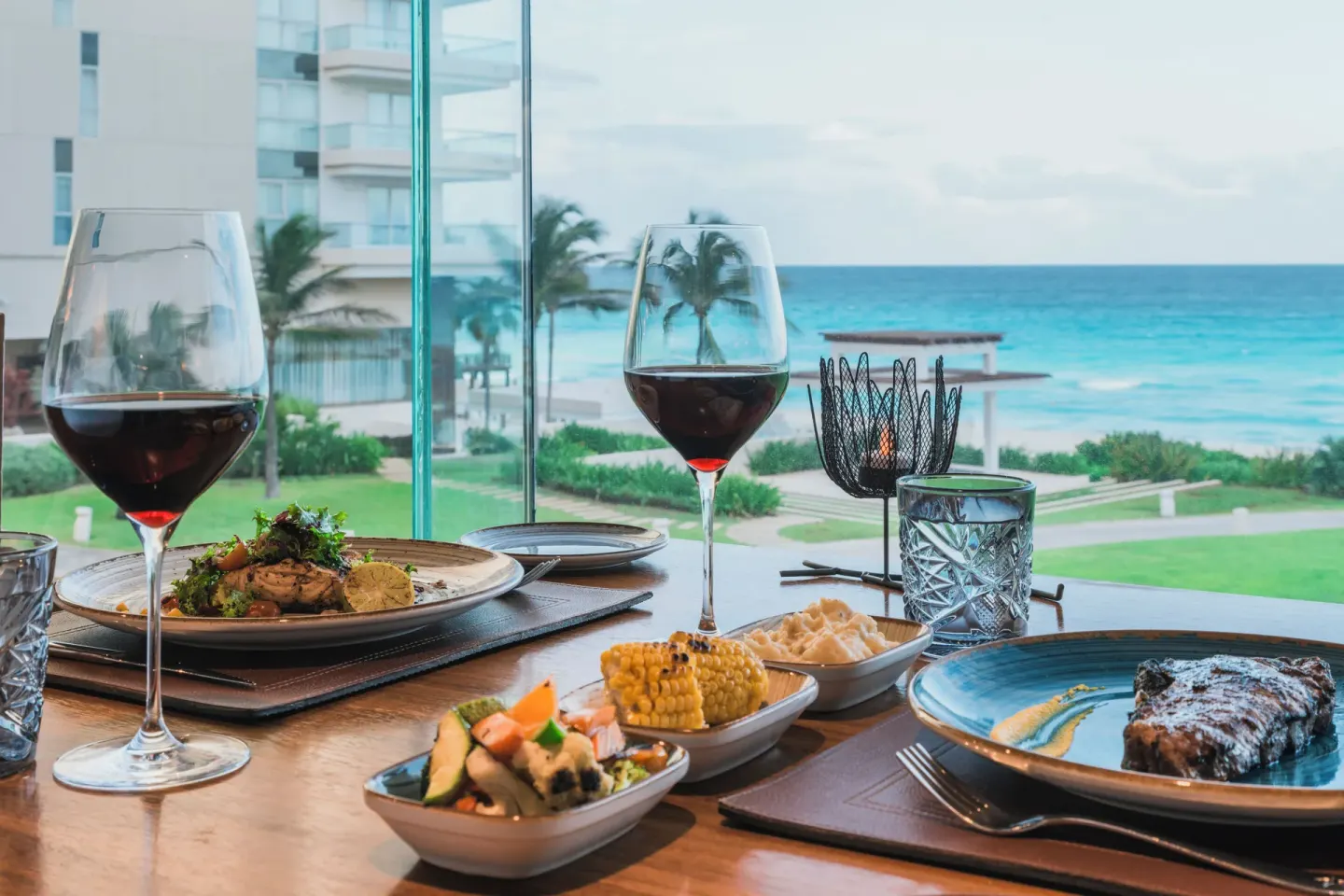 Steak dinner table by ocean-facing windows at Iberostar Selection Cancún.