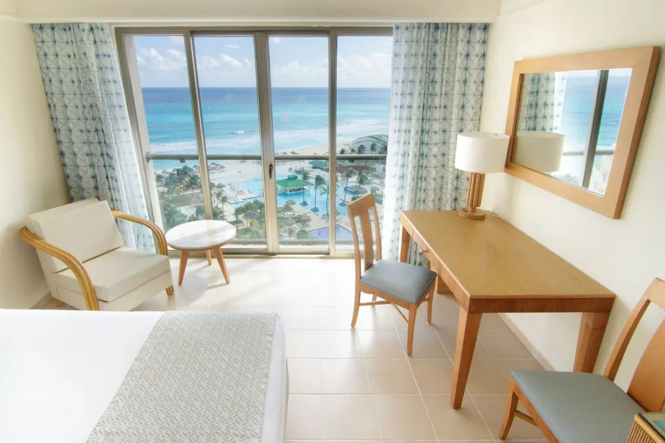 Premium Room Ocean View at Iberostar Selection Cancún with bed, desk, chairs, and wide Caribbean view.